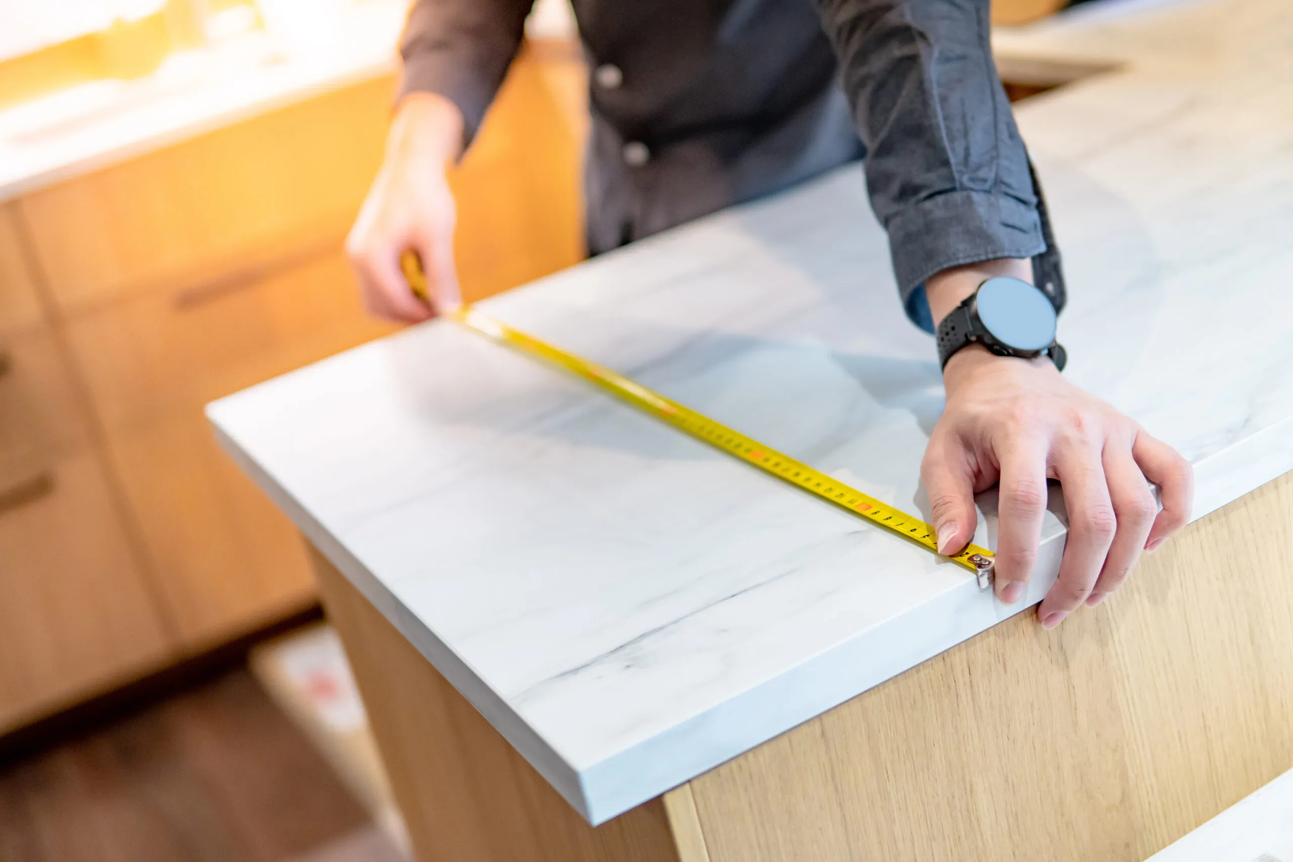 Granite installation upgrades technician measuring a white stone countertop in an Arizona kitchen