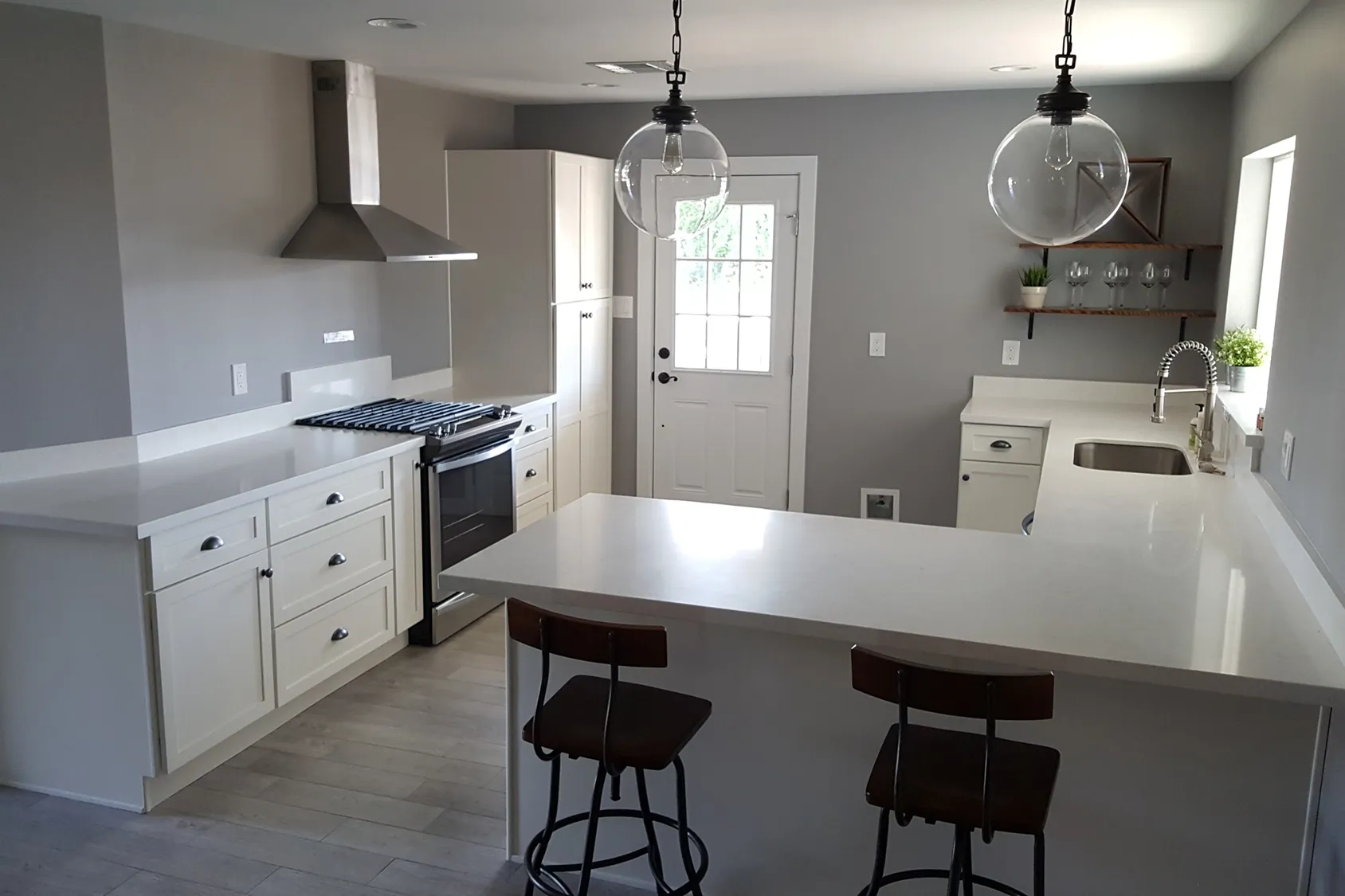 Granite kitchen countertops in Phoenix AZ with a white island, bar stools, and pendant lighting