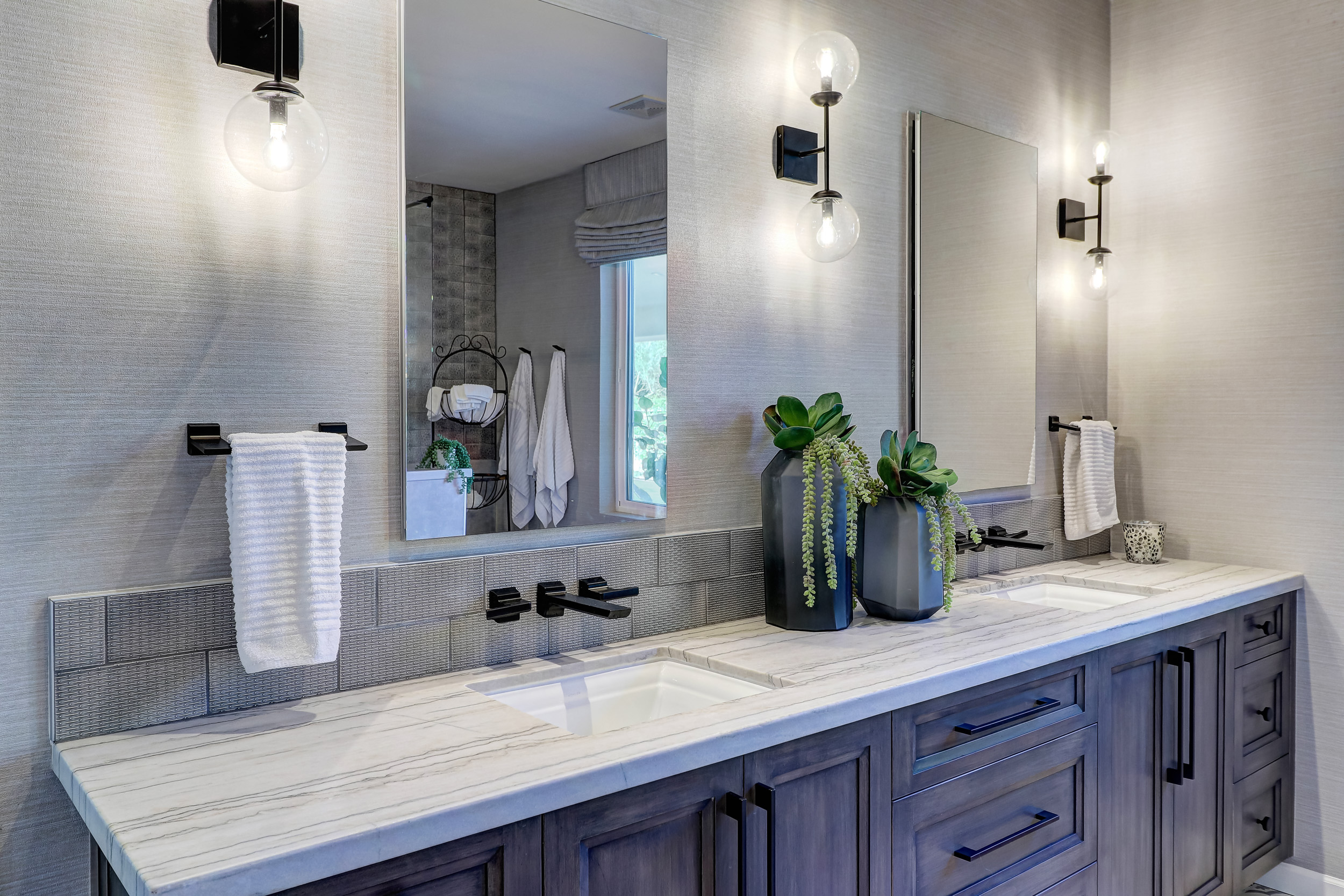 Double undermount sink granite bathroom vanity tops with gray cabinetry, matte black faucets, and modern wall sconces in a Phoenix master bathroom.