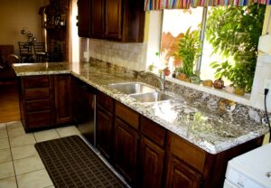 Granite kitchen countertop edge with eased profile over dark wood cabinets and stainless steel sink