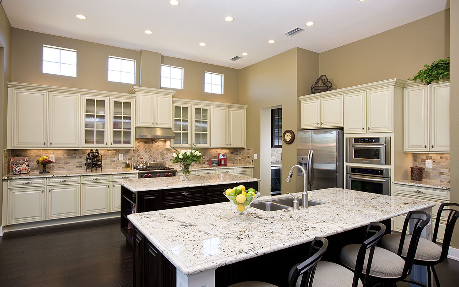 Kitchen with granite countertop edge on a large island and perimeter counters with white cabinetry