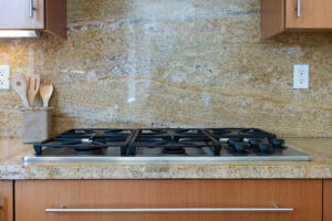Granite backsplash Phoenix kitchen with gas cooktop and wood cabinets