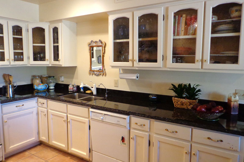 Black granite countertop Phoenix kitchen with white cabinets and glass doors